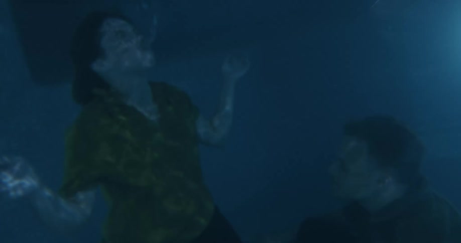 A man and woman dive under the water in the pool