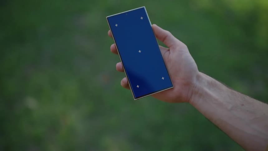 A mans hand holds up a smart phone as he walks