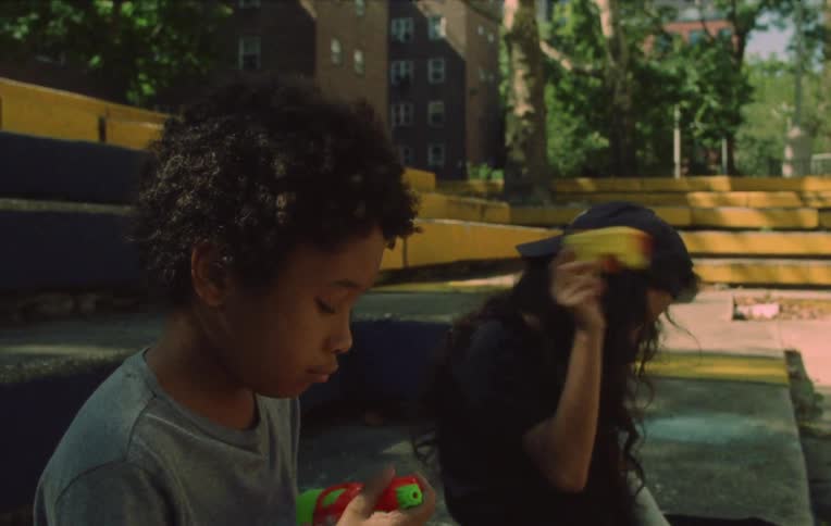 Two children sitting in a public area swinging toy guns