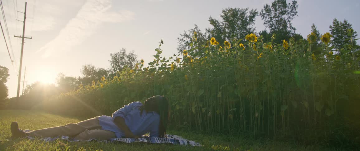 A man is laying down by the field of flowers