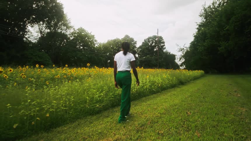 A woman walking in a garden with a sunflower