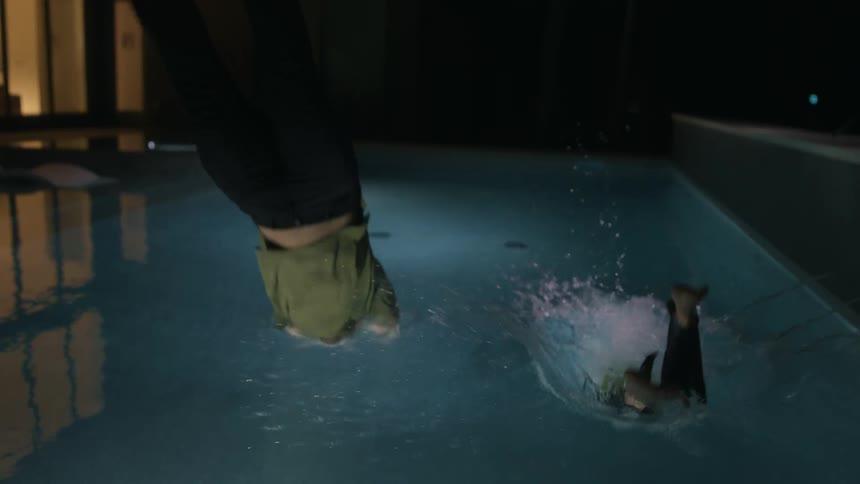 Two friends dive into the pool with their clothes on
