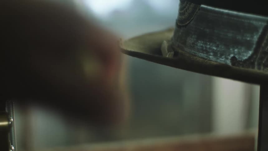Closeup of a hat and a hand beside it lowering a lever