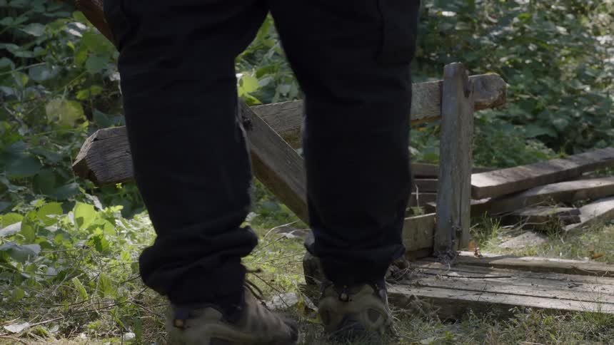 A man hammering a wooden table in an outdoor garden environment