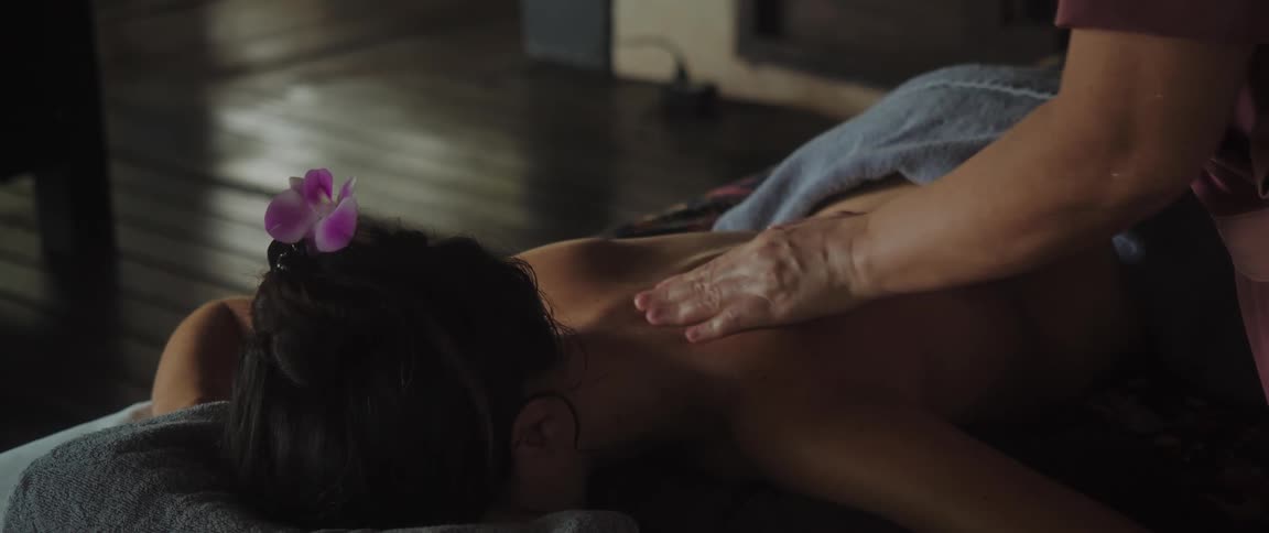 A woman lying down has her back massaged by another person