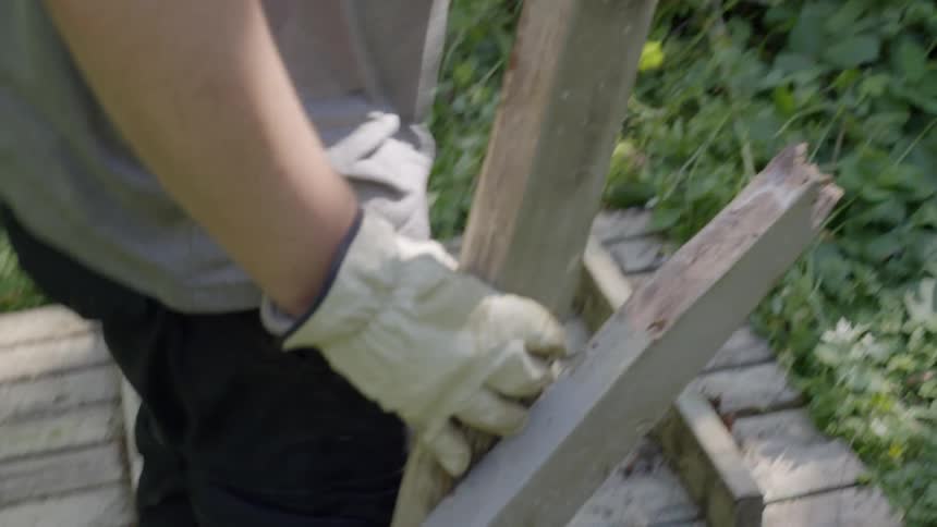 A man dismantles a wooden beam from a foundation and throws it into a pile