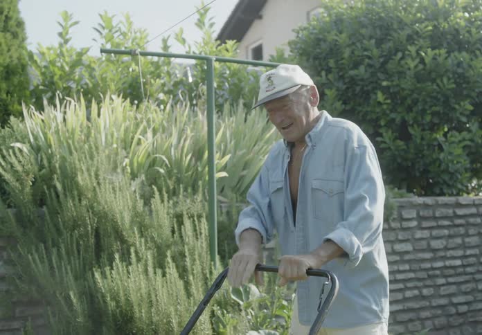 An elderly man starting a lawnmower and celebrating