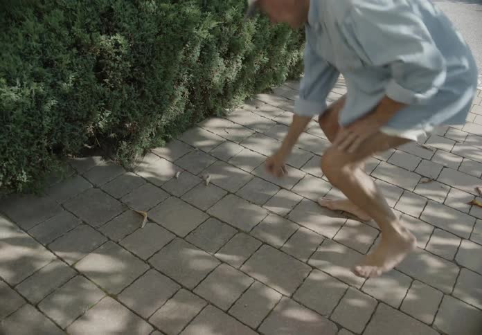 An old man picking up a small stick from the ground