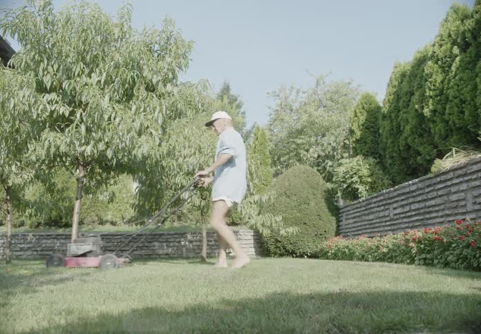 An elderly man cutting grass with his lawn mower