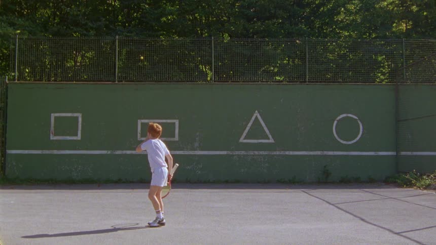 A redhaired boy is hitting a ball using a racket