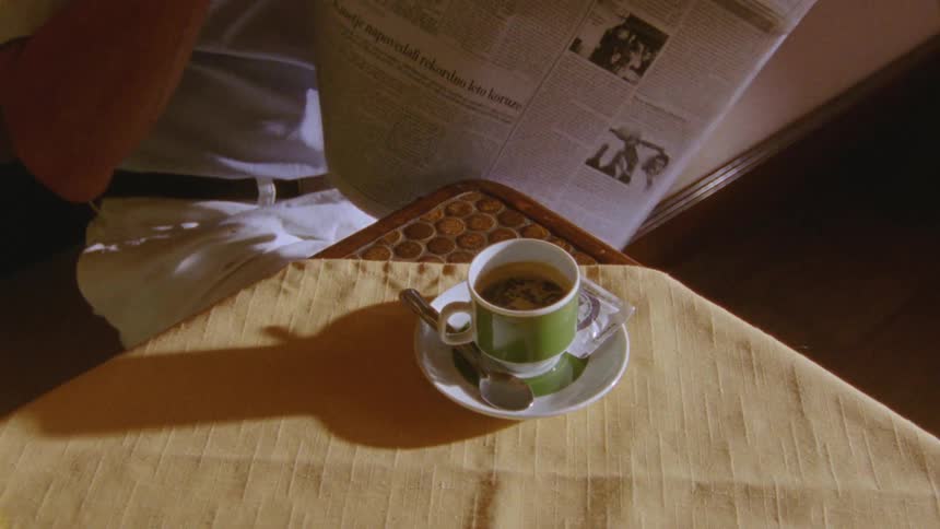 Man sits and reads newspaper while drinking beverage
