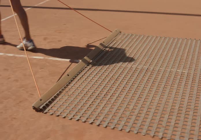 A person drags a device to clean the court