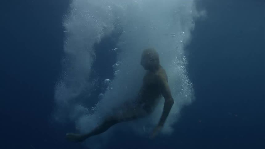 An elderly man is diving into a body of water