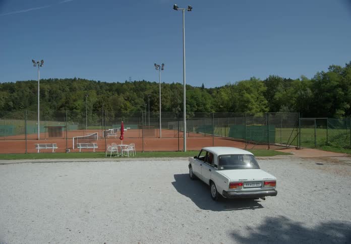 Elderly person parking their car in a location with tennis courts