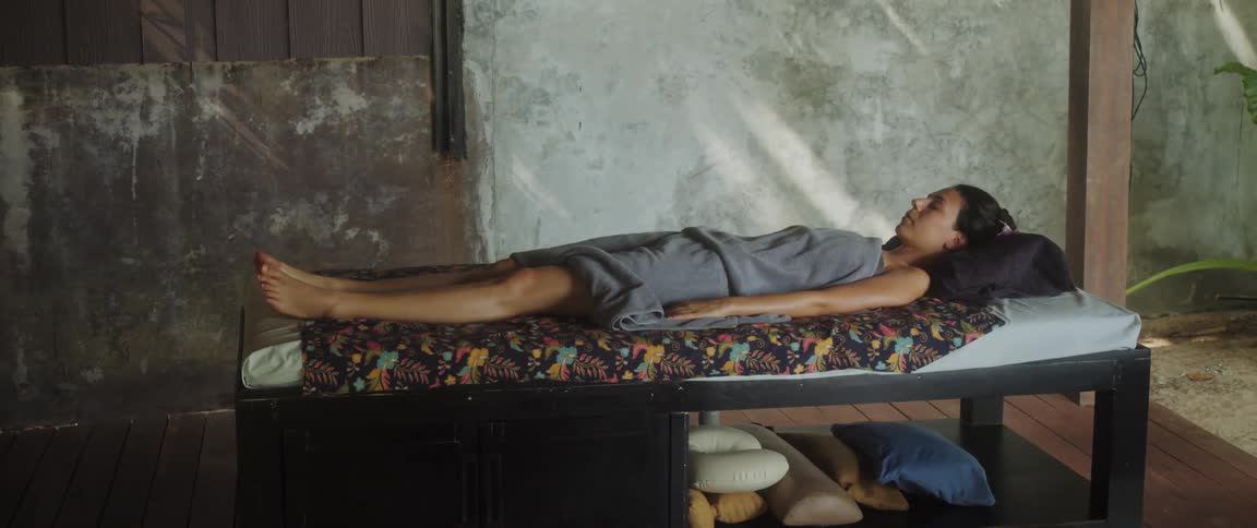 A woman lying on a massage bed with pillows
