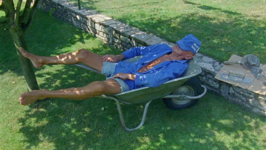 A man is sleeping in a wheel barrel