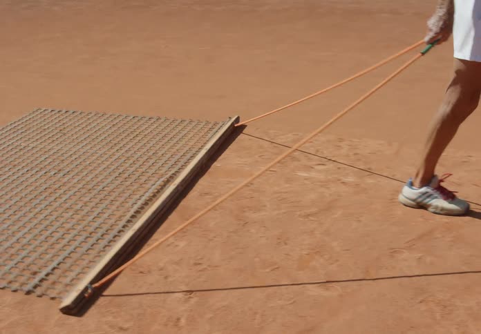 A person walking and dragging a fence onto the court
