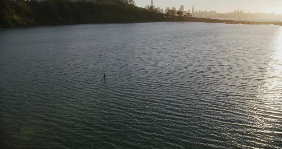 Person on a stand up paddle board on the San Francisco Bay at sunset from a cinema drone