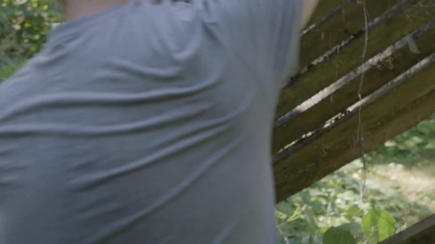 A gardener picks up an old wooden bench in the garden
