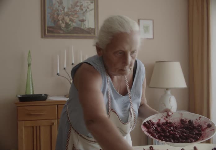 An old lady spreading out some berries over a table