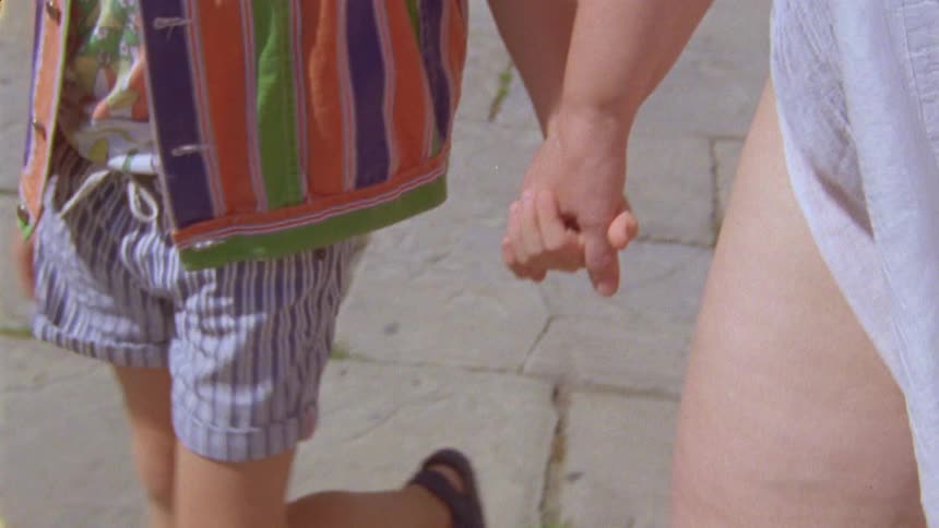 A redhaired boy walking hand in hand with his mother
