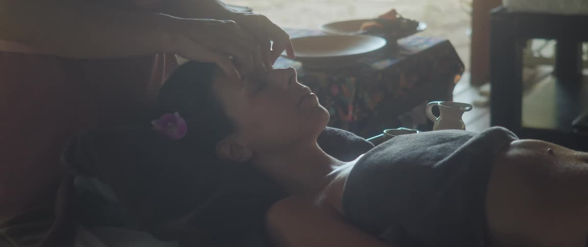 Woman massaging the forehead and face of a lady laying on her back