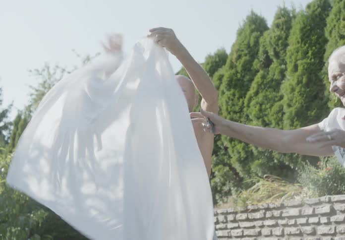 A man and woman hang laundry in the yard