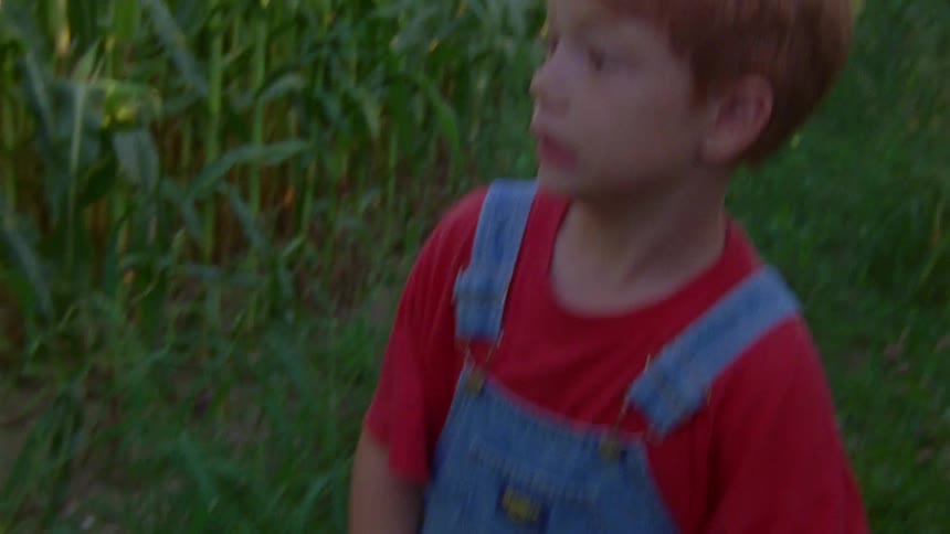 Red head boy runs through corn maze