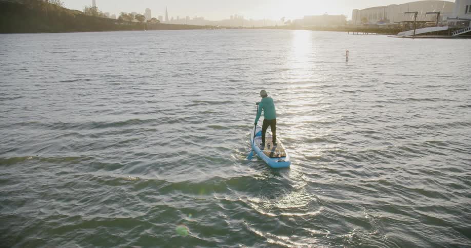 Man paddling on a stand up board at sunset on the San Francisco Bay