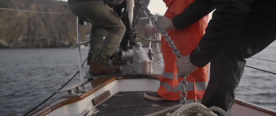 Men are pulling a chain onto a boat
