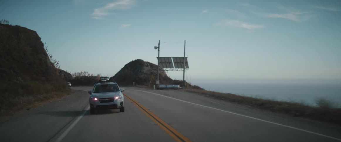 A car drives along a coastal roadway that overlooks the ocean