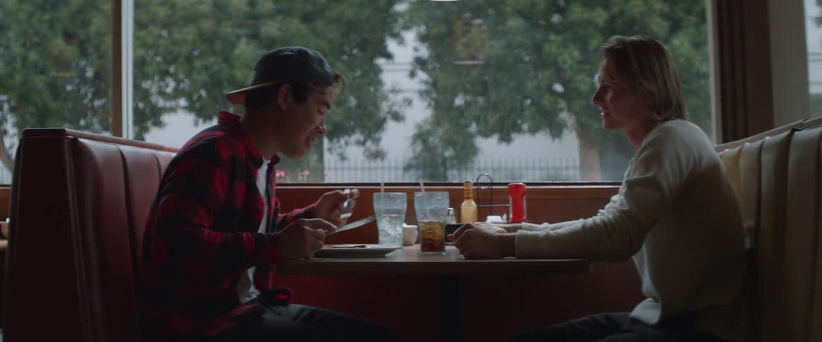 Two men sitting in a cafeteria talking and eating