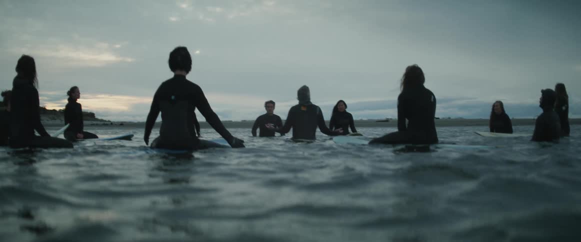 People on surfboards are in a circle in the water