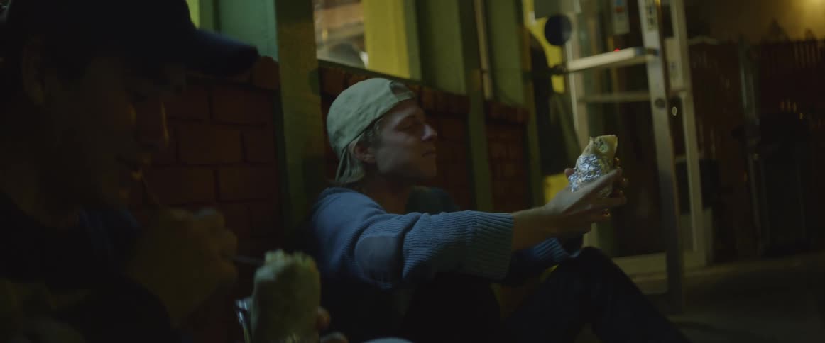 Two men are sitting outside eating at night