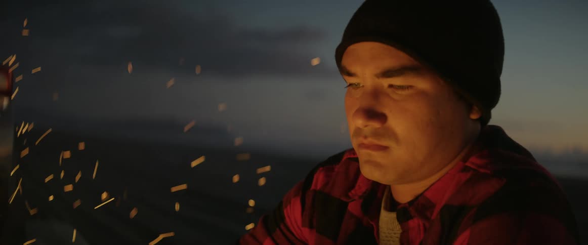 A pensive man lights a bonfire on the beach