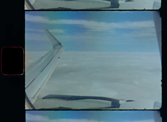 Aerial view from inside a small plane looking out of the window at the horizon with a blue sky on a sunny day while flying over the clouds while air traveling or an airplane trip on old film