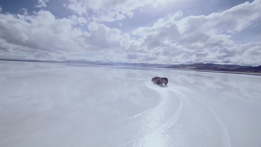 FPV footage of an offroad truck racing across the flooded Bonneville Salt Flats, a wide turn