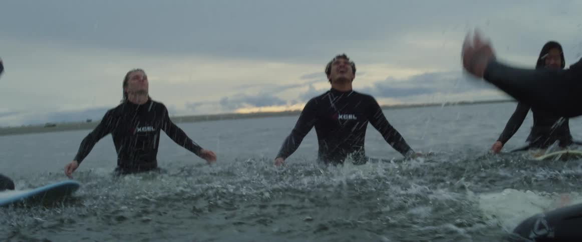 Group of surfers floating in the ocean playfully splash water
