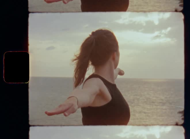 An independent and sportive woman with long brown hair in a pony tail stretching in nature overlooking the ocean during the day as the sun sets over the sea or water at the horizon representing power and strength gained by sports activities