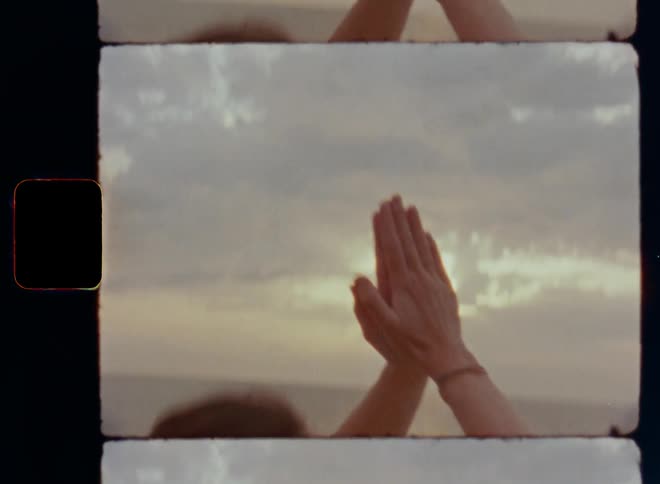 Close up of woman stretching doing yoga on beach during the day as she raises her arms and joins her hands in front of her heart to find inner peace and quietness during yoga pose or meditation while sitting cross-legged on the gravelly or rocky ground