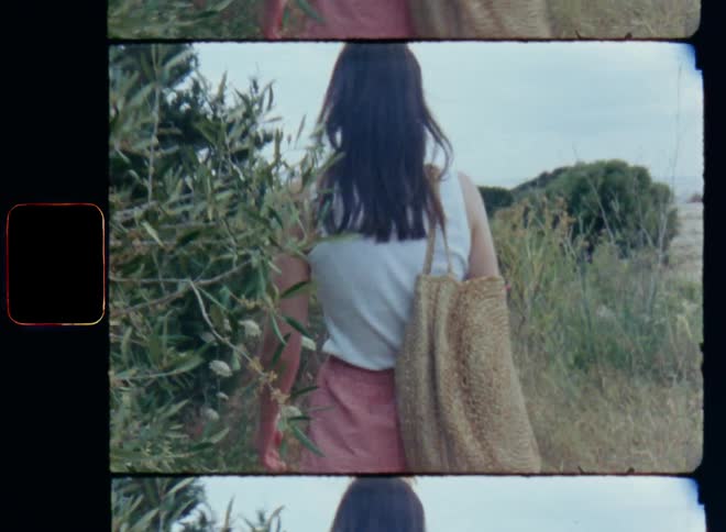 Young attractive woman walks along a wild trail through bushes and nature that leads towards a coastal area during the daytime looking for the beach or discovering the area on a sightseeing holiday or vacation trip or tour on a warm summer day