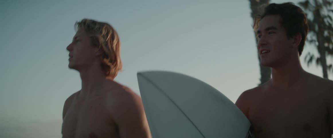 Two young people walking along the beach promenade with their surfboards