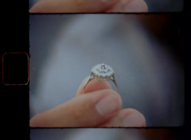 Super 8mm close up of male hand of a young man holding a silver diamond engagement ring wile kneeling on his knees and proposing with shaky fingers in a nervous and intense romantic moment with anticipation hope and love