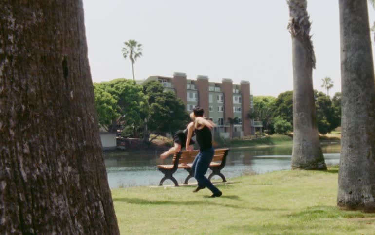 A man dancing and a woman who is dancing while standing on a bench
