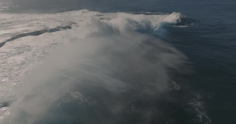 A huge wave breaking into the sea and lifting a lot of water upwards