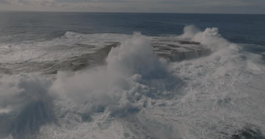 Aerial view of waves crashing on a promontory in the ocean