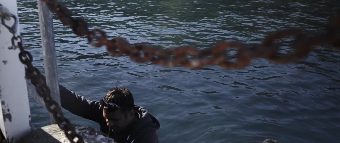 A man climbs down a ladder into a raft below