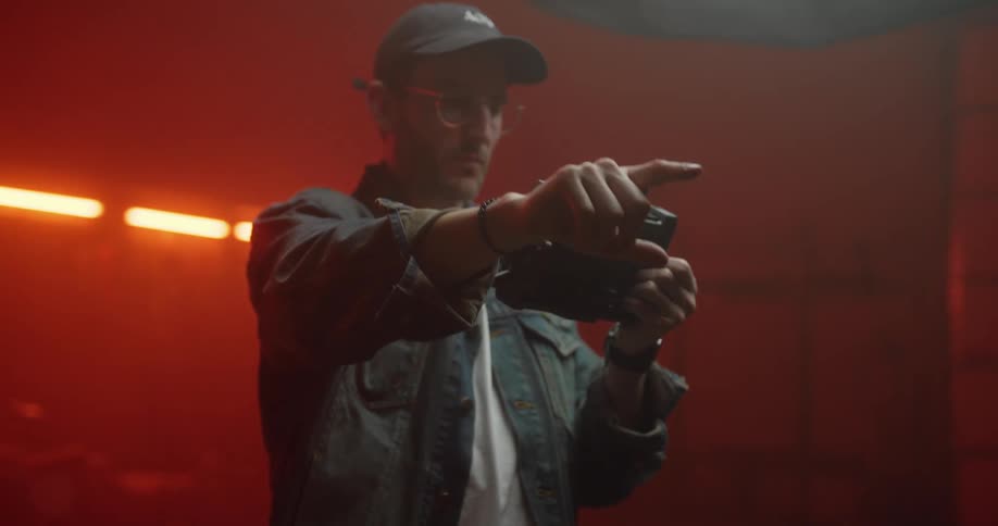 A man in a studio looks at a device and points giving orders