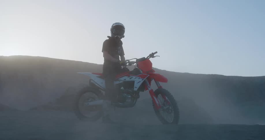 A person on top of a motocross bike on a sandy hill