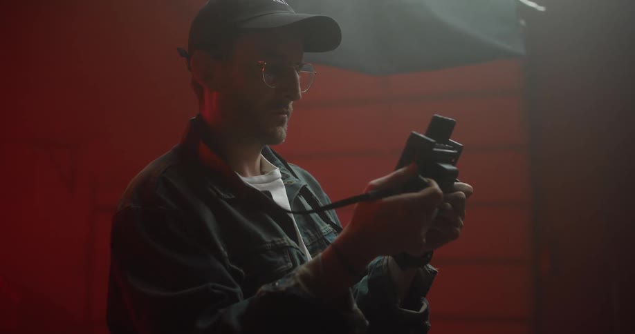 A man in a studio checks a device then gives orders
